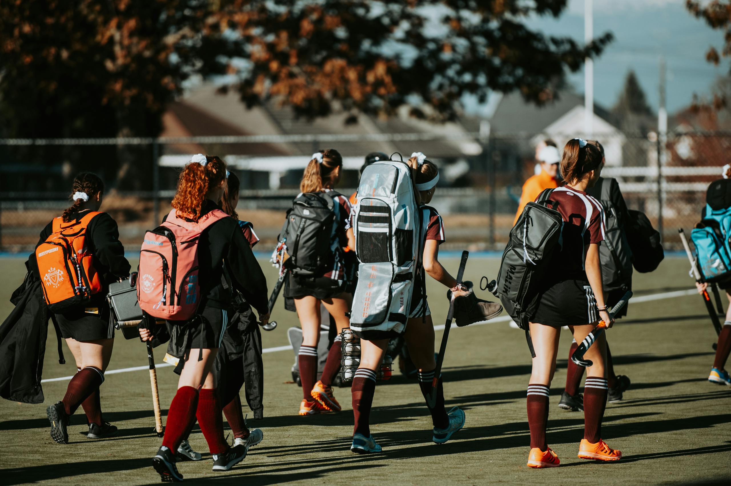 Group of young athletes with gear heading to field hockey practice.